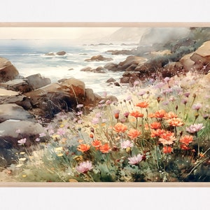 May include: A framed watercolor painting depicting a coastal landscape with a rocky shoreline meeting the ocean. The foreground features a vibrant cluster of orange and light pink wildflowers growing among green grasses and dark brown rocks.
