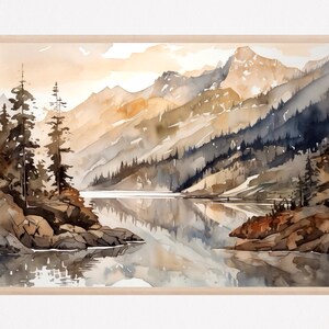 Op de afbeelding: Aquarel landschapskunstafdruk met een serene bergmeerscène. Het kunstwerk toont een reeks kleuren, waaronder bruin, blauw en geel, met reflecties in het water. De afdruk is ingelijst in een licht houten frame.