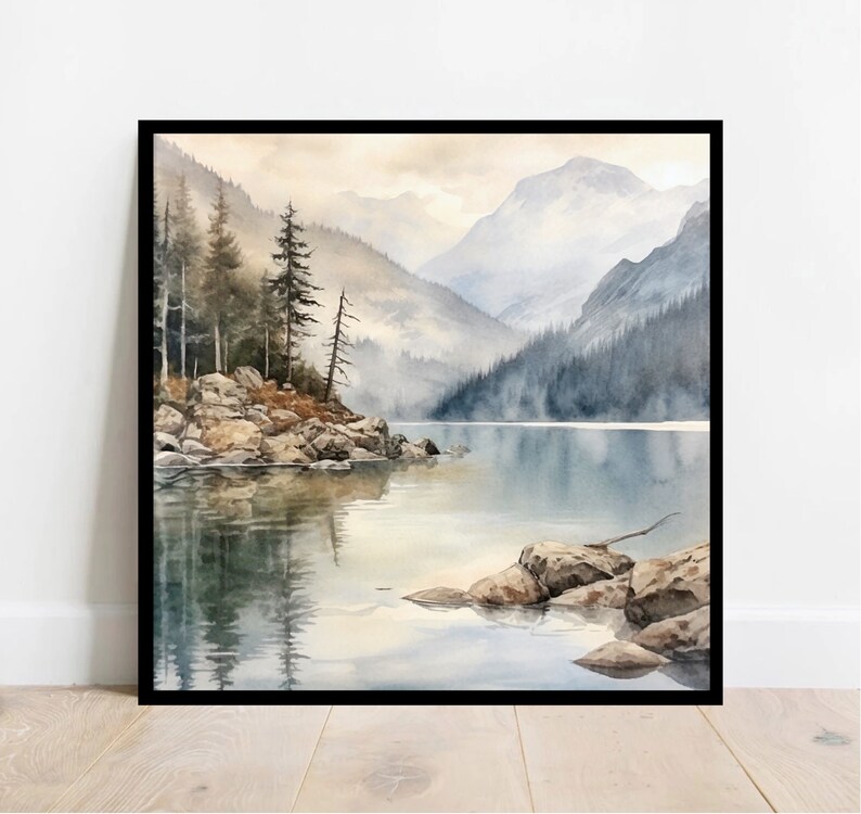 Op de afbeelding: Een aquarel schilderij van een bergmeer sc&egrave;ne met een klein eiland op de voorgrond. Het eiland is bedekt met rotsen en bomen, en het meer wordt omringd door bergen. De lucht is zacht blauw, en het water is kalm en reflecterend blauw.