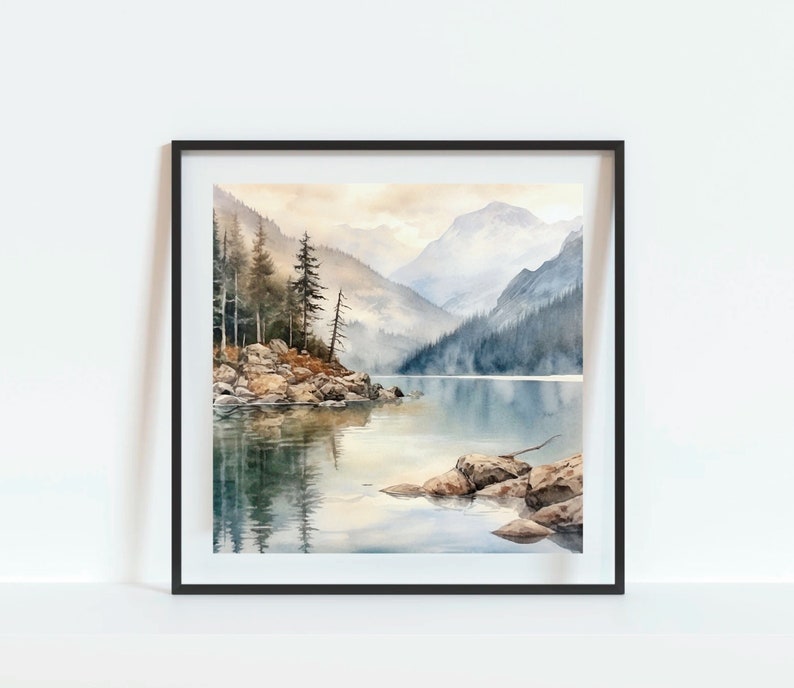 Op de afbeelding: Een aquarel schilderij van een bergmeer sc&egrave;ne met een klein eiland op de voorgrond. Het eiland is bedekt met bomen en rotsen, en het meer wordt omringd door bergen. De lucht is zacht blauw, en het water is een kalm, reflecterend oppervlak.