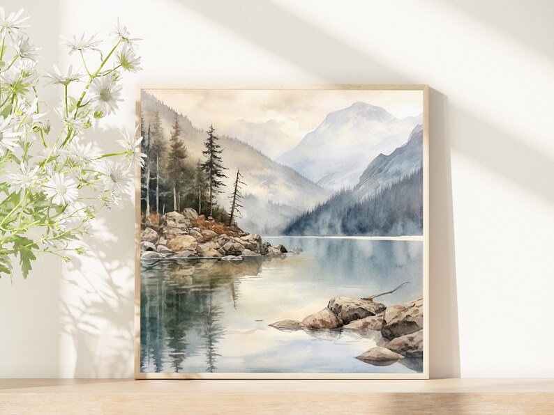 Op de afbeelding: Een aquarel schilderij van een bergmeer sc&egrave;ne met een klein eiland op de voorgrond. Het meer is omringd door bergen en bomen, en het water is lichtblauw. De lucht is lichtgrijs, en er zijn wolken in de lucht.