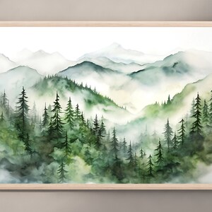 Puede incluir: Pintura a la acuarela de un paisaje monta&ntilde;oso con un bosque en primer plano. La obra presenta capas de tonos verdes y azules, con un marco de madera clara. Las monta&ntilde;as brumosas y los &aacute;rboles crean una escena natural serena.