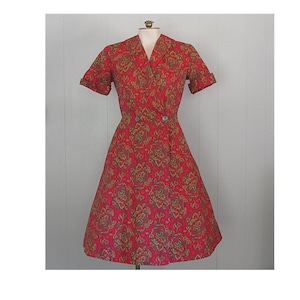 May include: A red and gold floral print dress with a double-breasted button closure and short sleeves.
