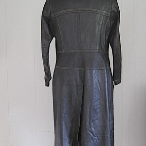 May include: A long black leather coat with a collar and a single button closure. The coat has a seam down the back and a center back vent.
