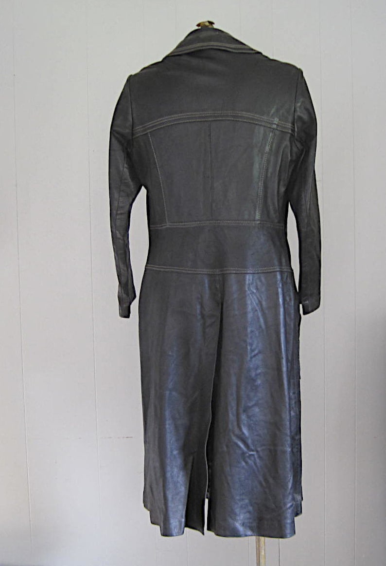 May include: A long black leather coat with a collar and a single button closure. The coat has a seam down the back and a center back vent.