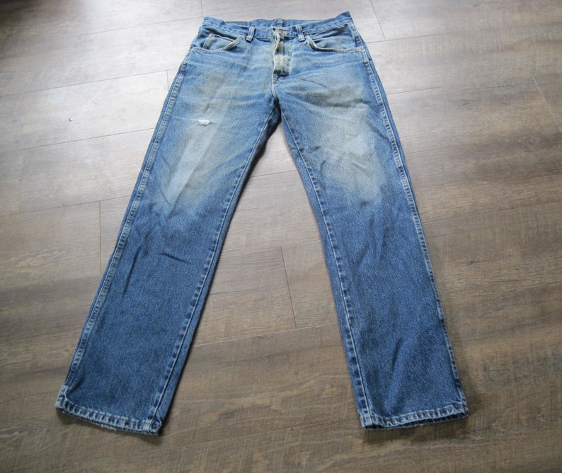 May include: A pair of blue denim jeans with a button fly and a faded look. The jeans have a straight leg and are made of a soft, comfortable fabric.