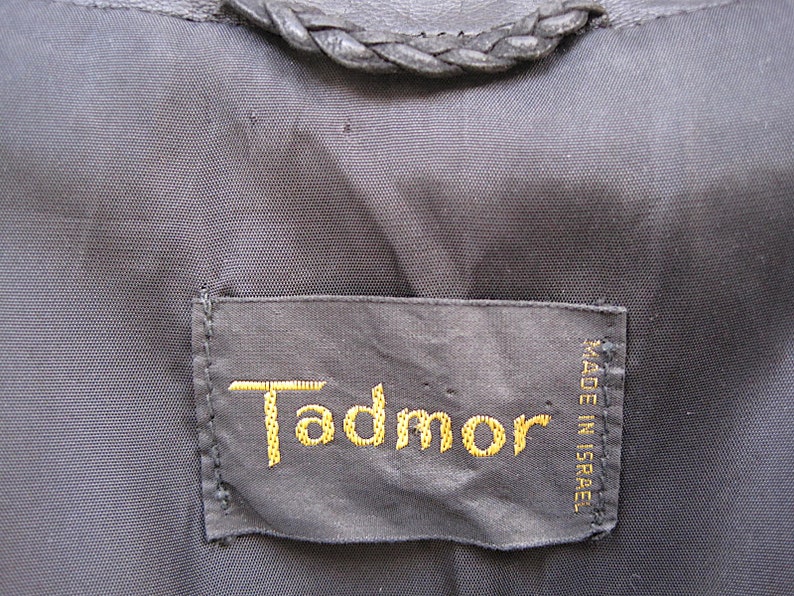 May include: A black leather label with gold stitching that reads "Tadmor" and "MADE IN ISRAEL".