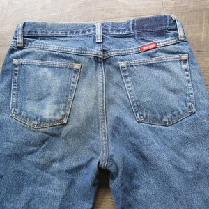 May include: A pair of blue denim jeans with a red Wrangler label on the back pocket.
