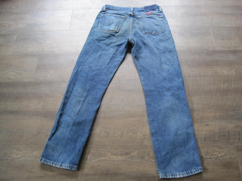 May include: A pair of blue denim jeans with a red label on the back pocket.