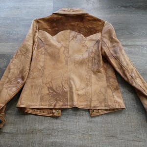 Peut inclure: Une veste en cuir marron avec un empi&egrave;cement en daim et une fermeture &agrave; nouer. La veste a un aspect vieilli et une couleur marron d&eacute;lav&eacute;e.