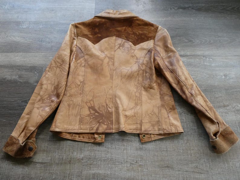 Peut inclure: Une veste en cuir marron avec un empi&egrave;cement en daim et une fermeture &agrave; nouer. La veste a un aspect vieilli et une couleur marron d&eacute;lav&eacute;e.