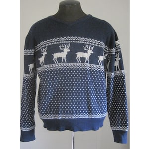 May include: A navy blue sweater with a white reindeer pattern. The sweater has a V-neck and long sleeves.