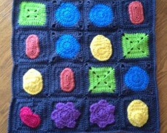 May include: A crocheted baby blanket with a variety of colorful shapes, including circles, squares, and stars. The blanket is made with a dark blue yarn and has a textured surface.
