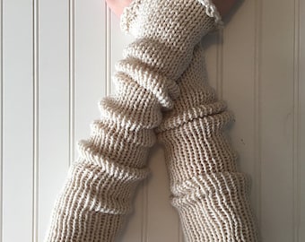 May include: A pair of off-white, hand-knitted arm warmers featuring a ribbed texture with horizontal gathered detailing. The arm warmers have a simple, straight silhouette that extends from the wrist to the forearm, finished with a delicate crocheted edge.