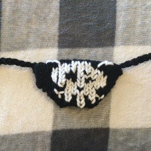 May include: Black and white knitted skull mask with a black cord.