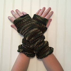 Peut inclure: Une paire de mitaines sans doigts de couleur verte, marron et noire avec un motif camouflage.