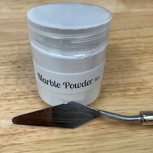 Peut inclure: Un pot en plastique blanc avec une &eacute;tiquette blanche sur laquelle est inscrit "Marble Powder 4oz". Un couteau &agrave; palette en m&eacute;tal argent&eacute; se trouve &agrave; c&ocirc;t&eacute; du pot.