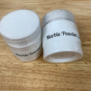 Peut inclure: Deux pots en plastique blanc contenant de la poudre blanche. Les pots ont des &eacute;tiquettes noires indiquant "Marble Powder".