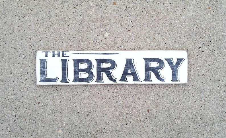 Op de afbeelding: Een wit houten bord met zwarte letters met de tekst "THE LIBRARY".