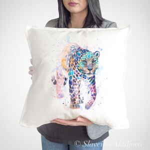 May include: A white pillow with a watercolor painting of a colorful leopard. The leopard is walking towards the viewer and has blue, purple, and pink spots.