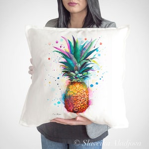 Pode incluir: Almofada quadrada branca com um vibrante design de abacaxi em aquarela. O abacaxi tem uma coroa colorida e um corpo laranja texturizado. Salpicos de azul, rosa e amarelo envolvem a fruta, criando um tema tropical.