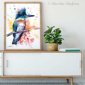 May include: Watercolor painting of a blue and brown kingfisher bird perched on a branch with colorful leaves and a white background.