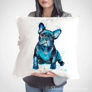 Puede incluir: Almohada blanca con una pintura de acuarela de un bulldog francés azul. El perro está sentado y mirando hacia la derecha. El fondo es blanco con salpicaduras de acuarela azul.