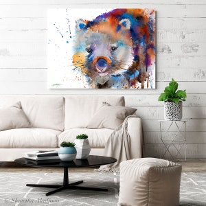 May include: Watercolor painting of a wombat with blue, orange, and yellow colors. The wombat is looking directly at the viewer. The background is white with splatters of paint.