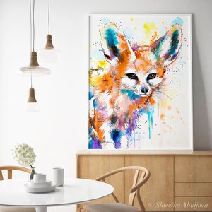 Puede incluir: Pintura acuarela de un zorro fennec con tonos naranja, azul y morado. El zorro est&aacute; mirando directamente al espectador con orejas grandes y un hocico blanco. El fondo es amarillo claro con salpicaduras blancas.