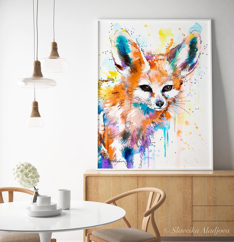 Puede incluir: Pintura acuarela de un zorro fennec con tonos naranja, azul y morado. El zorro est&aacute; mirando directamente al espectador con orejas grandes y un hocico blanco. El fondo es amarillo claro con salpicaduras blancas.