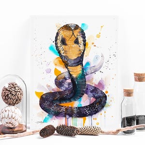 Puede incluir: Pintura acuarela de una cobra con un cuerpo de patrón amarillo y negro, sobre un fondo de salpicaduras de acuarela de colores.