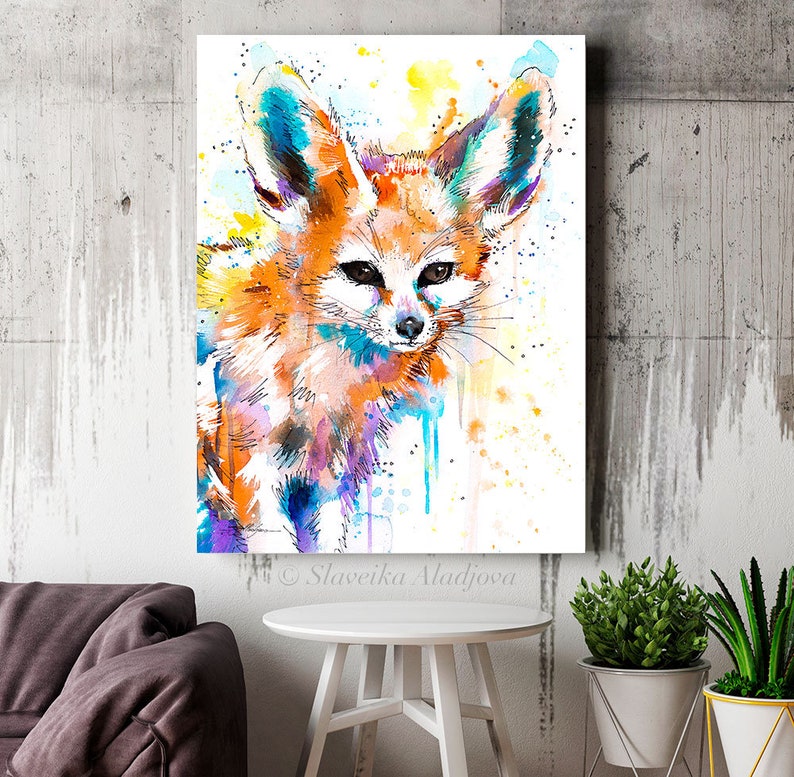 Puede incluir: Pintura acuarela de un zorro fennec con orejas grandes, pelaje naranja y detalles azules y morados. El fondo es blanco con salpicaduras de acuarela amarilla y azul.