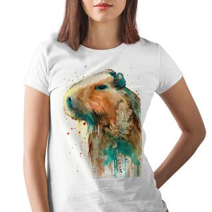 May include: A white t-shirt with a watercolor illustration of a capybara. The capybara is brown and has a teal and green watercolor effect around it.