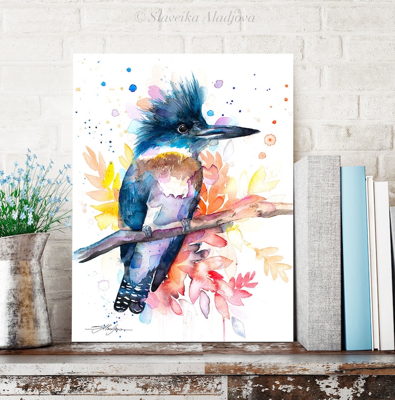 May include: Watercolor painting of a blue and purple kingfisher perched on a branch with colorful flowers and leaves. The background is white with colorful watercolor splatters.