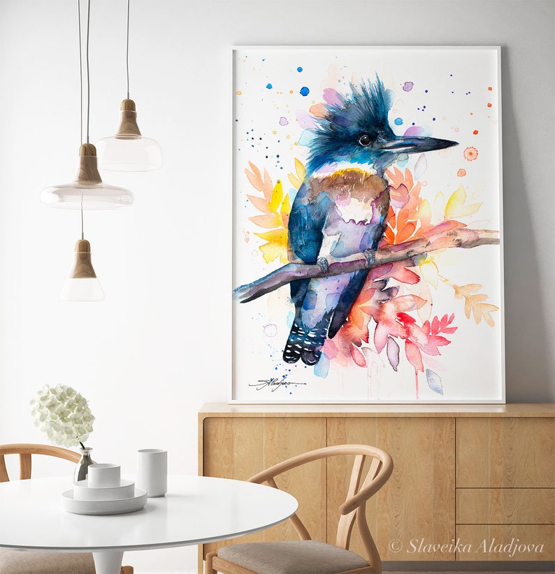 May include: Watercolor painting of a blue and purple belted kingfisher perched on a branch with colorful flowers and leaves. The background is white with watercolor splatters.