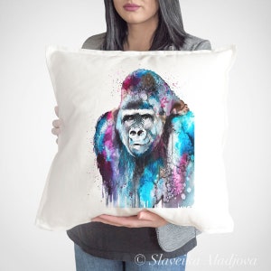 Könnte beinhalten: Quadratisches weißes Kissen mit einem Aquarellgemälde eines Gorillas. Der Gorilla ist mit lebendigen Farbspritzern in Blau, Rosa und Lila dargestellt. Das Kunstwerk ist von Slaveika Aladjova signiert.
