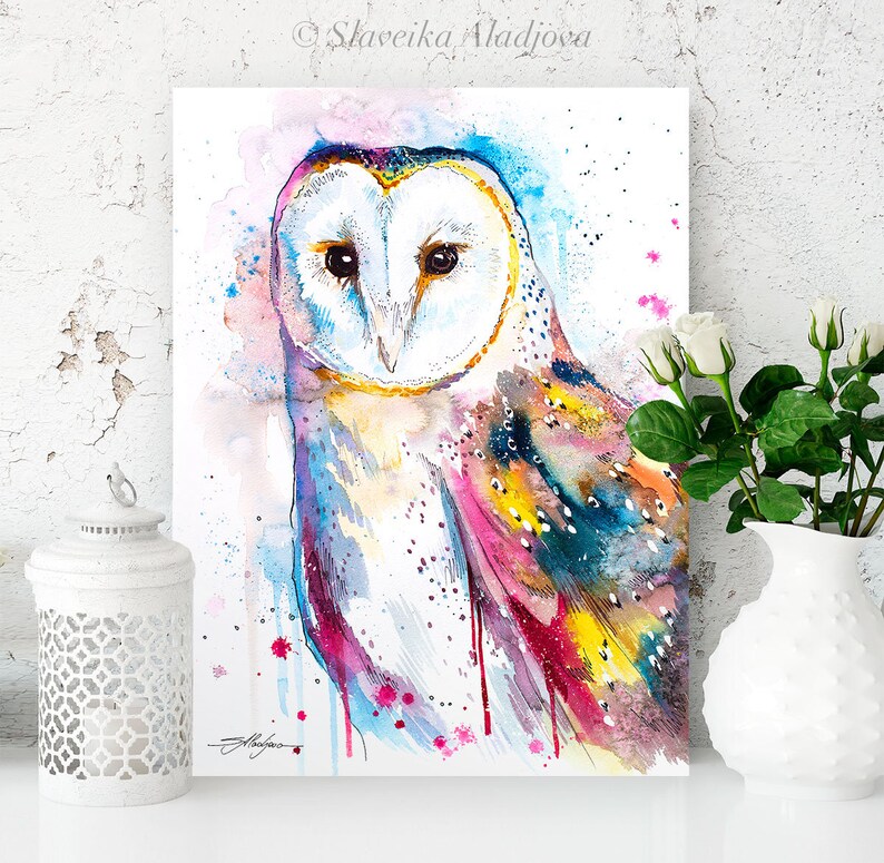 May include: A watercolor painting of a barn owl with colorful splashes of pink, blue, yellow, and green. The owl's eyes are black and its feathers are white.