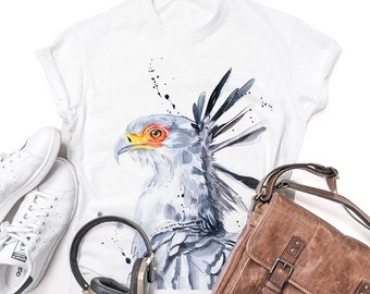 May include: White t-shirt featuring a watercolour illustration of a Secretary Bird. The bird is facing left and has a long, spiky crest. The background is white with black splatters.