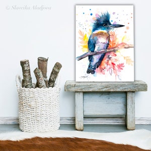 May include: Watercolor painting of a blue and brown kingfisher perched on a branch with colorful flowers and leaves. The background is white with blue and orange watercolor splatters.
