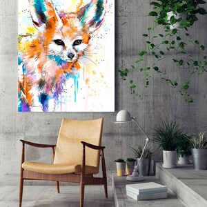 Puede incluir: Pintura acuarela de un zorro fennec con orejas grandes, pelaje naranja y blanco y ojos azules. El fondo es amarillo claro con salpicaduras de azul y morado.