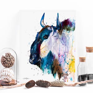 May include: Watercolor painting of a blue and purple wild ox with horns. The painting has a white background with splashes of yellow, pink, and brown paint.
