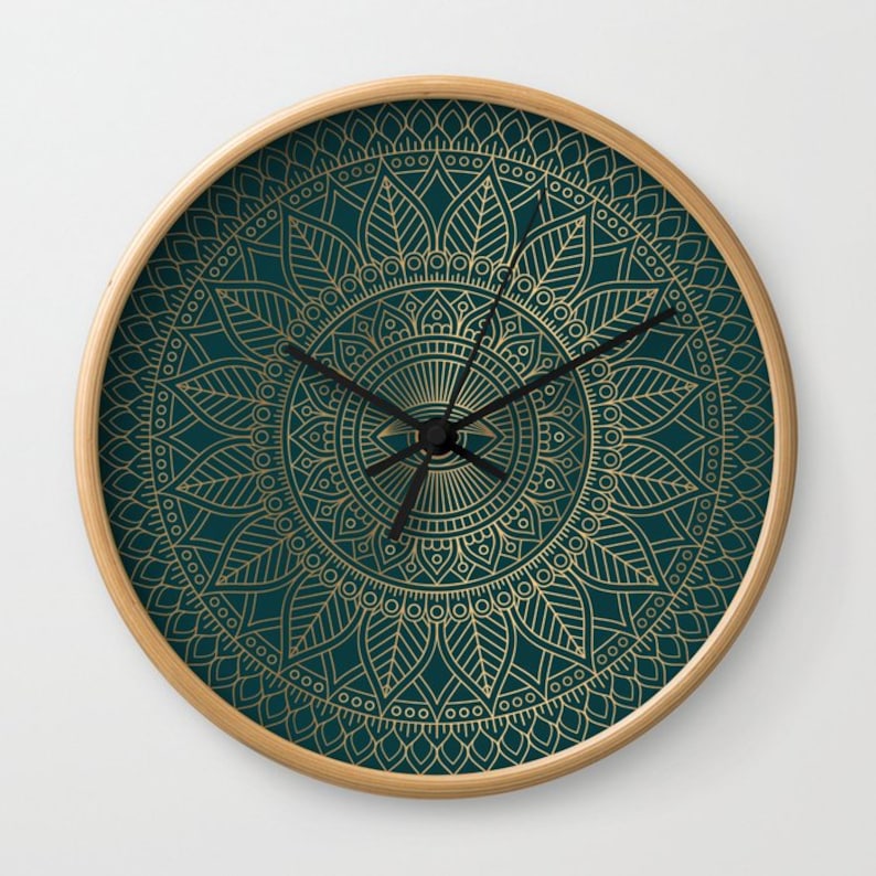 Pu&ograve; includere: Un orologio da parete rotondo con un design a mandala dorato su uno sfondo blu scuro. L'orologio ha lancette nere e un bordo dorato.