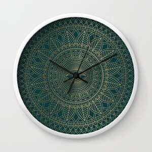 Pu&ograve; includere: Un orologio bianco con un design a mandala dorato su sfondo verde scuro. Il quadrante dell'orologio &egrave; al centro del mandala e ha lancette nere.