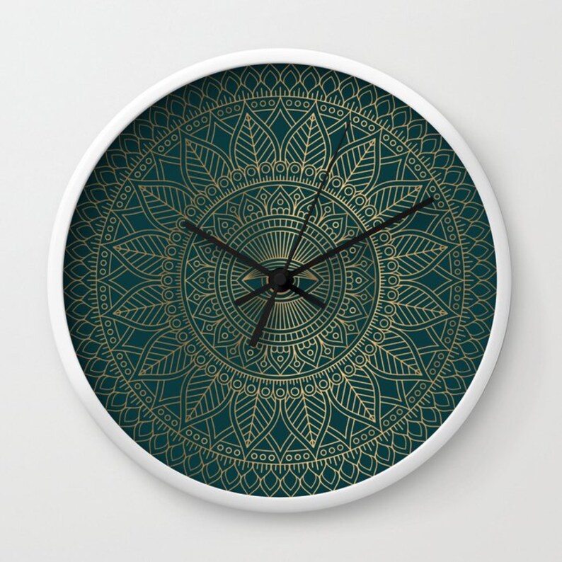 Pu&ograve; includere: Un orologio bianco con un design a mandala dorato su sfondo verde scuro. Il quadrante dell'orologio &egrave; al centro del mandala e ha lancette nere.