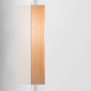 Pu&ograve; includere: Primo piano del lato di un orologio in legno con una finitura marrone chiaro.