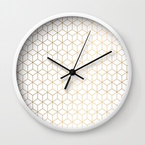 May include: A white clock with black hands and a gold geometric pattern on the face.