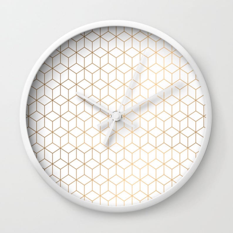 May include: White wall clock with a gold geometric pattern. The clock has a white face and gold hands.
