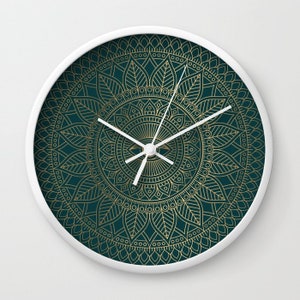 Pu&ograve; includere: Un orologio bianco con un design a mandala dorato su sfondo verde scuro. Il quadrante dell'orologio &egrave; bianco con lancette dorate.