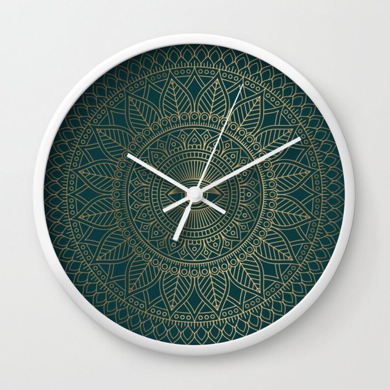Pu&ograve; includere: Un orologio bianco con un design a mandala dorato su sfondo verde scuro. Il quadrante dell'orologio &egrave; bianco con lancette dorate.