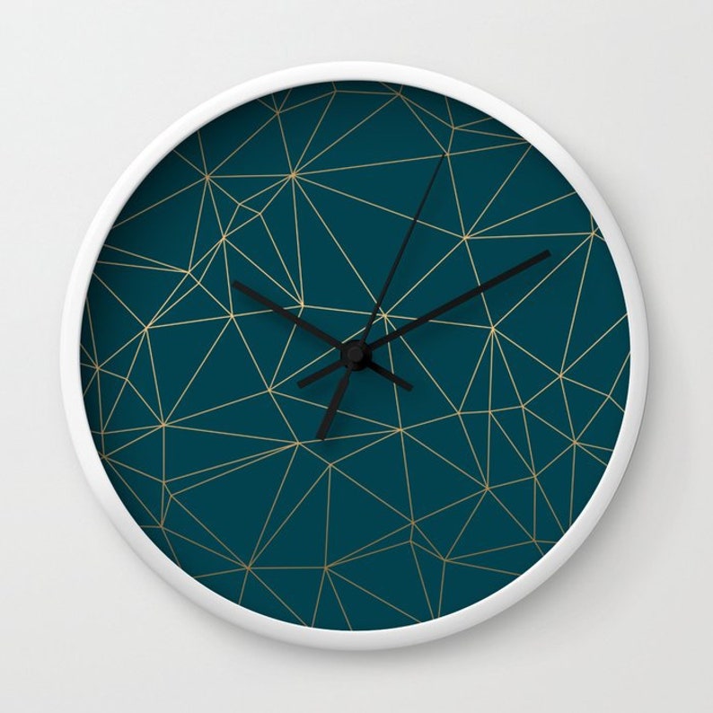 May include: A white clock with a teal blue face and gold geometric lines. The clock hands are black.